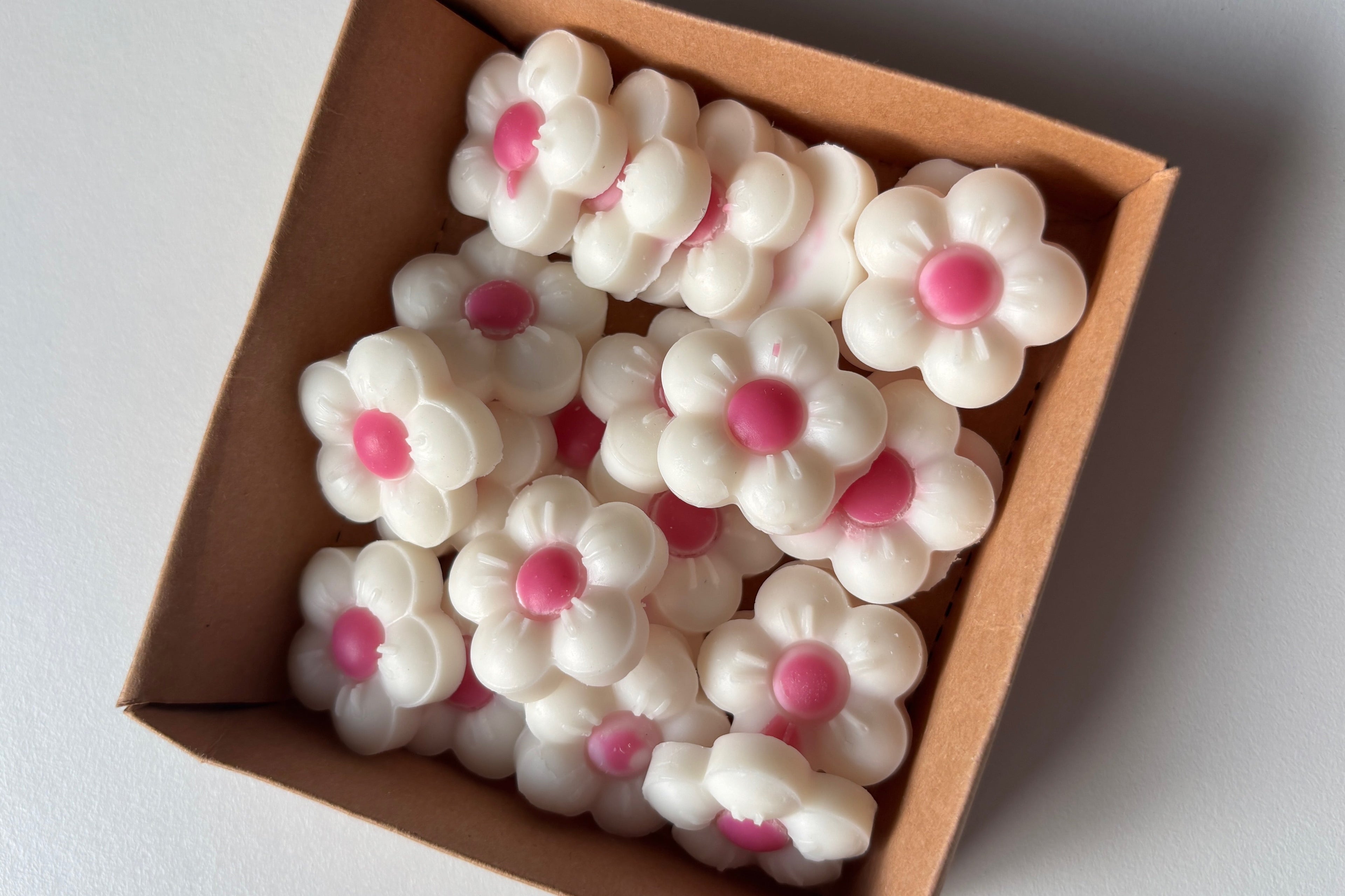 Box of white flowers with pink centers on a light gray background
