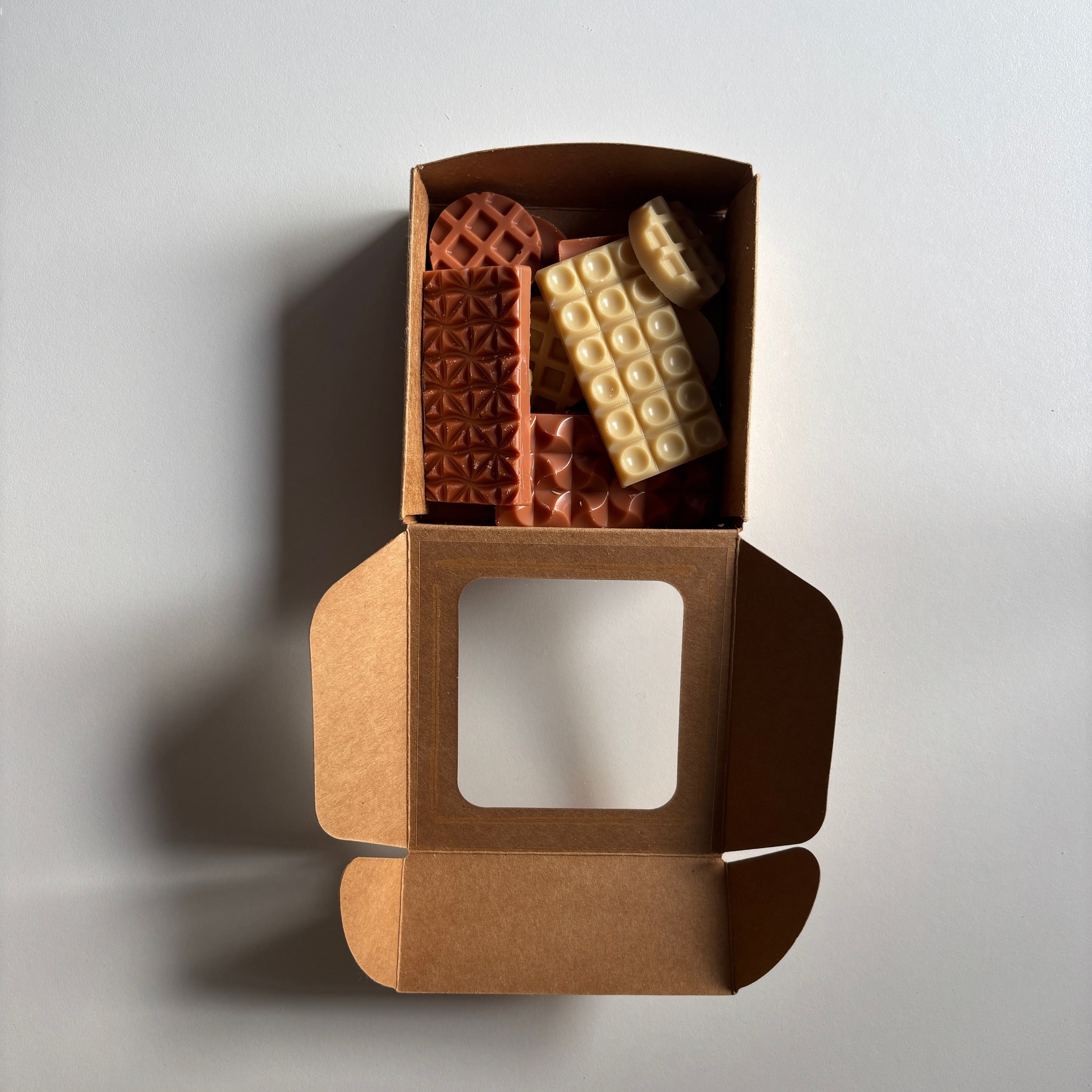 Open brown cardboard box with waffle-patterned chocolate bars on a light gray background