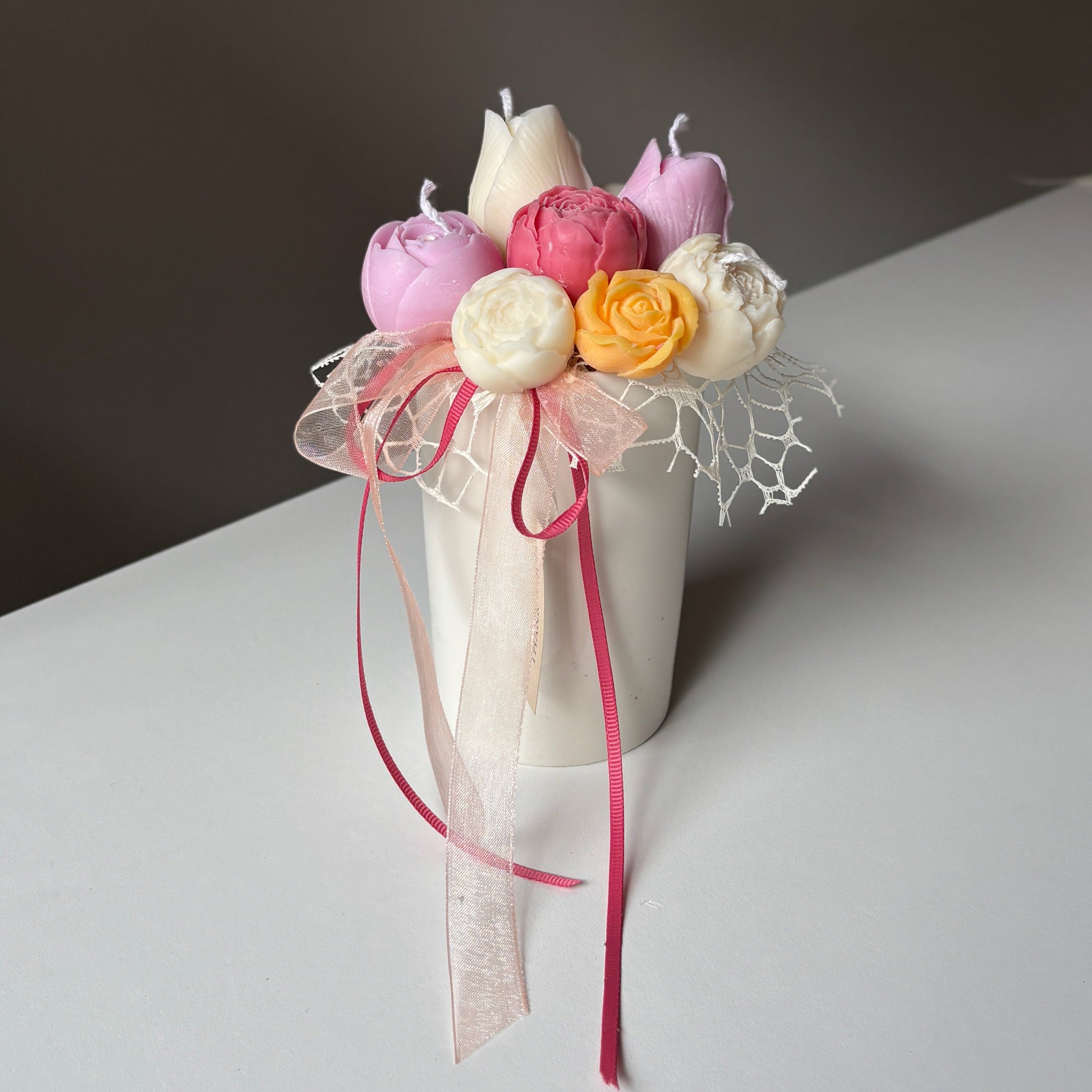 Decorative bouquet with flowers and ribbons in a vase on a plain background