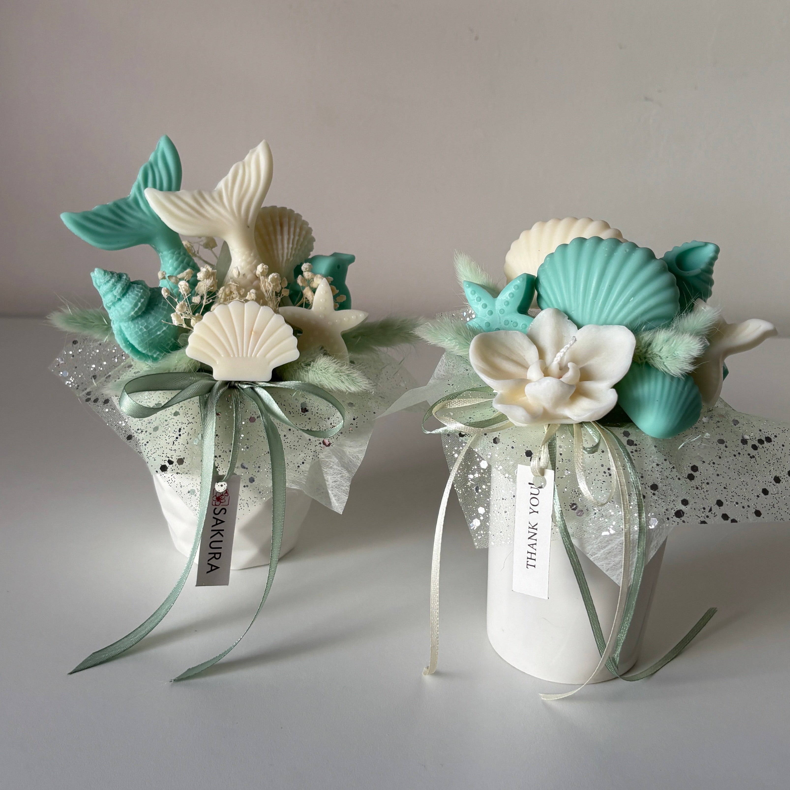 Two decorative items with shells and flowers on a gray background