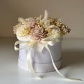 Decorative flower arrangement in a white box with a ribbon on a light background